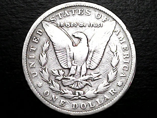 Silver dollar coin with an eagle design and 'In God We Trust' on a black background
