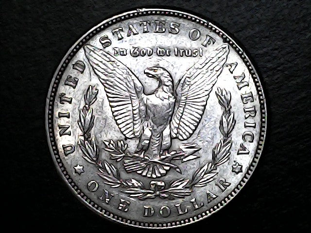 Silver dollar coin with an eagle design on a black background