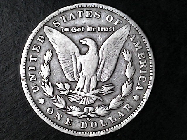 Silver Dollar with an eagle design, 'In God We Trust' and 'O' inscriptions on a black background