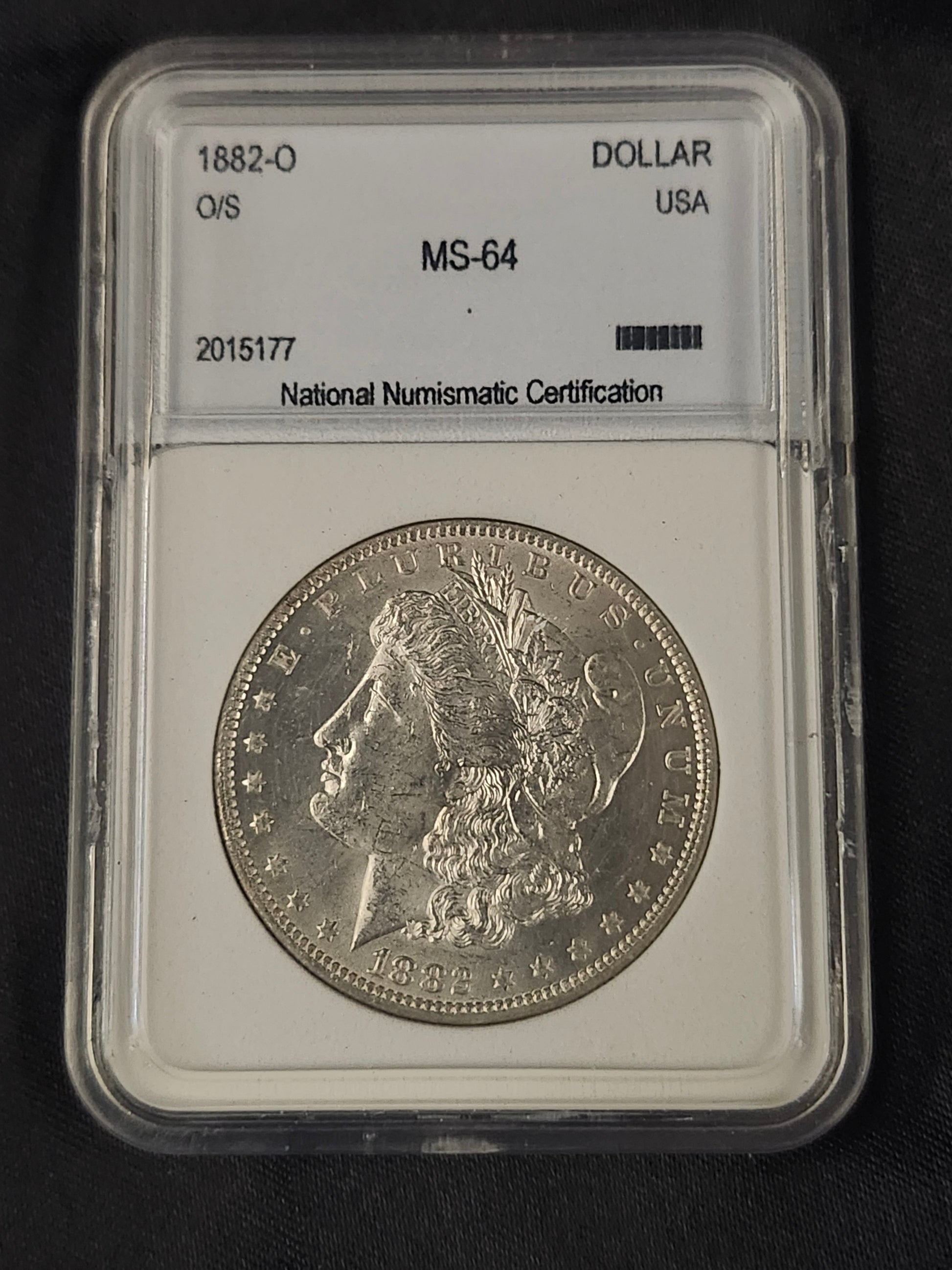 Silver Morgan dollar coin in a protective holder with grading information.