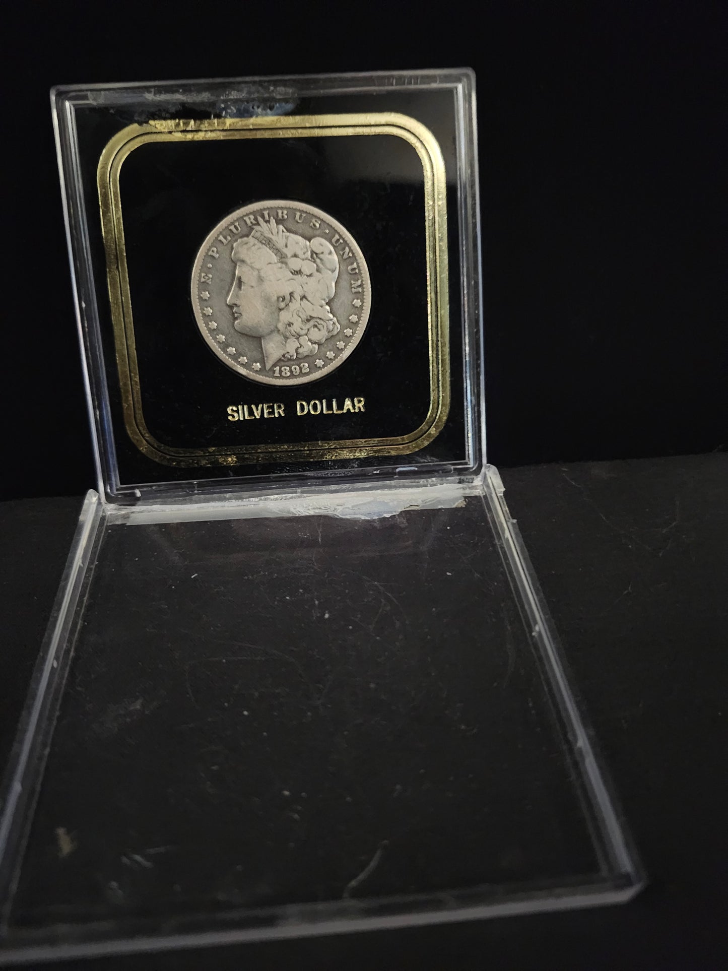 Silver Morgan dollar in a clear protective case on a black background