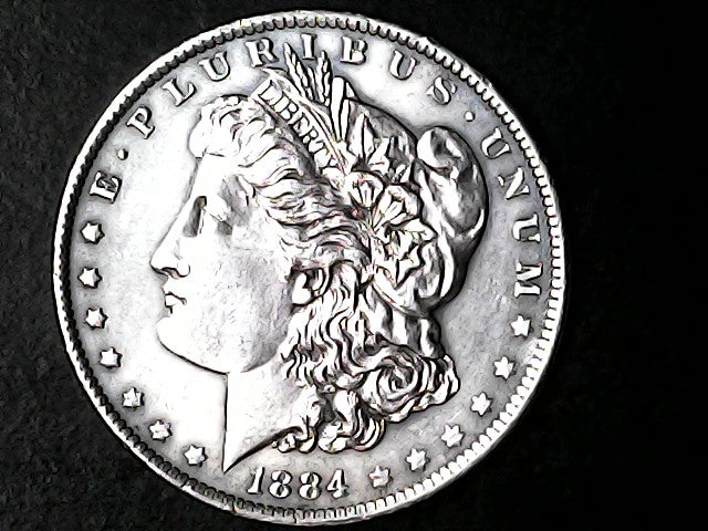 Silver Morgan Dollar Left-facing profile of Liberty wearing a Phrygian cap, with 'LIBERTY', "E PLURIBUS UNUM" and '1884' inscriptions on a black background with case