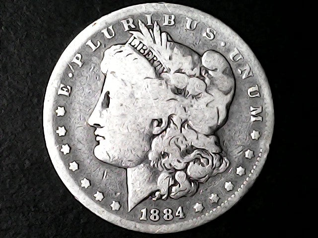 Silver Morgan dollar coin from 1884 with 'E Pluribus Unum' and 'Liberty' inscriptions on a dark background.
