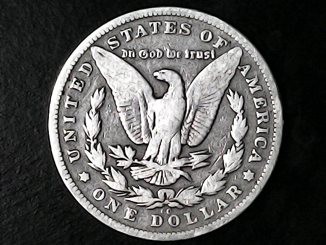 Silver Dollar with an eagle design, 'In God We Trust' and "CC" inscription on a black background