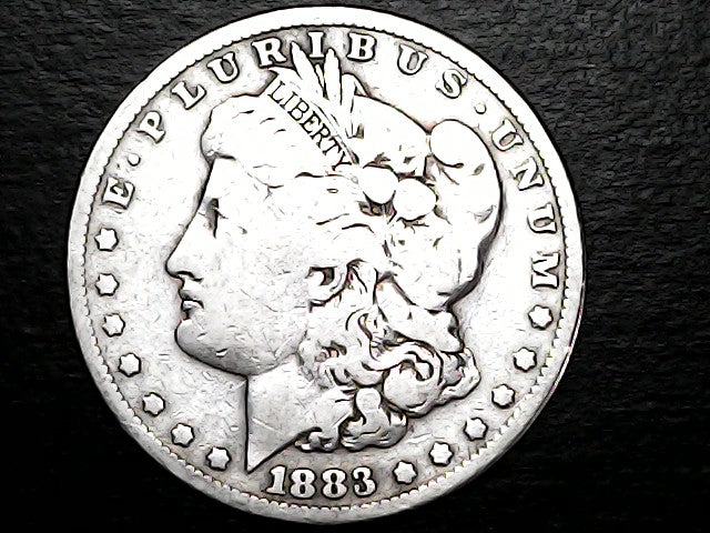 Silver Morgan Dollar Left-facing profile of Liberty wearing a Phrygian cap, with 'LIBERTY', "E PLURIBUS UNUM" and '1883' inscriptions on a black background with case