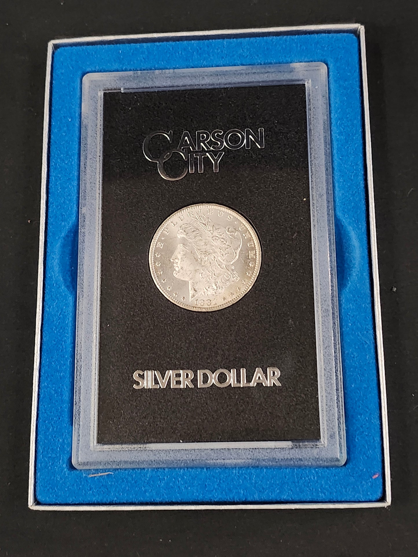 Silver dollar coin in a Carson City holder on a black background