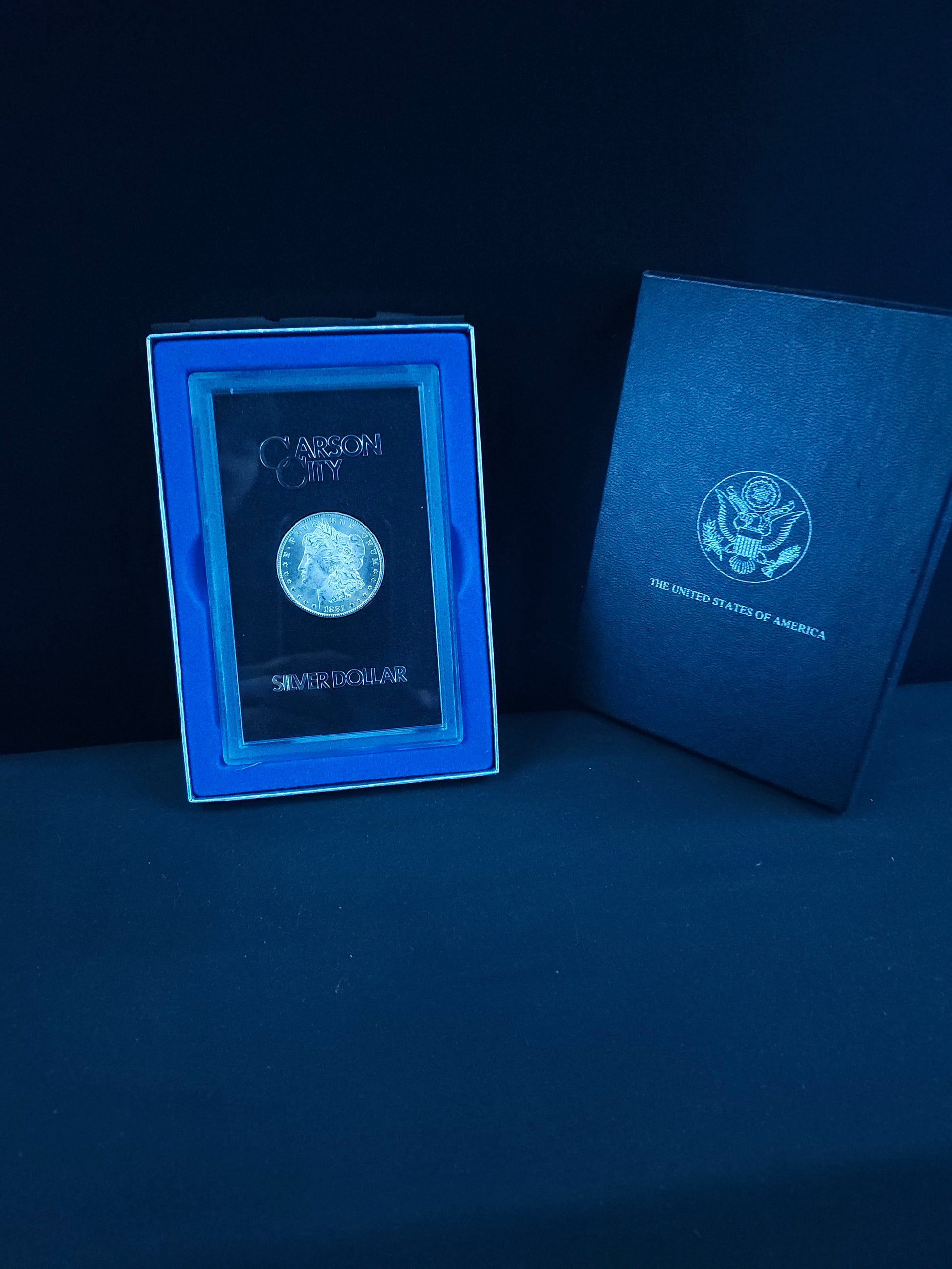 Two blue boxes with embossed designs on a dark surface