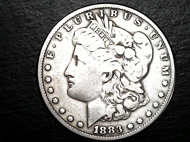 Silver Morgan Dollar Left-facing profile of Liberty wearing a Phrygian cap, with 'LIBERTY', "E PLURIBUS UNUM" and '1883' inscriptions on a black background with case