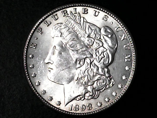 Silver Morgan Dollar Left-facing profile of Liberty wearing a Phrygian cap, with 'LIBERTY', "E PLURIBUS UNUM" and '1898' inscriptions on a black background with case