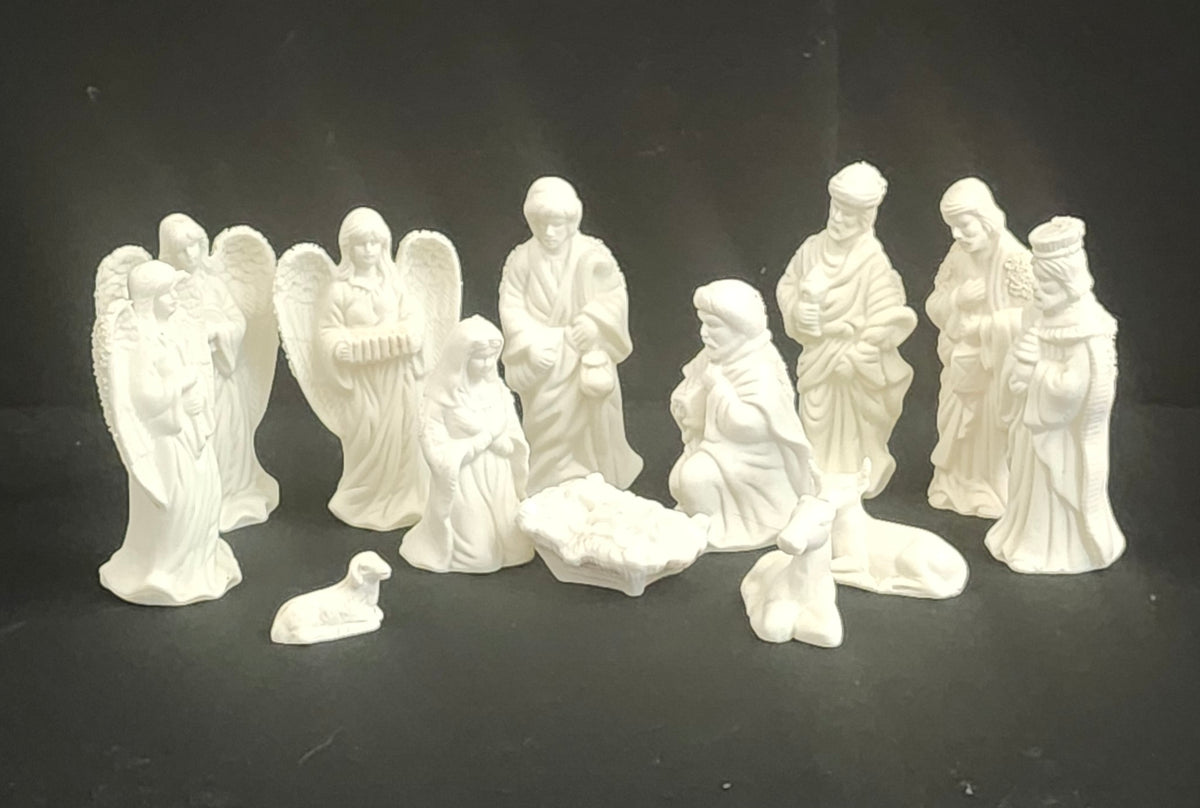 A set of white ceramic Christmas nativity figurines including angels, the baby Jesus, Mary, Joseph, three wise men, cow, horse, and a small sheep, arranged on a black background.