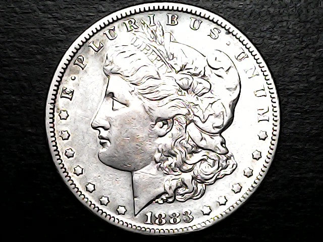 Silver coin with a profile of a person and 'Morgan' inscription on a dark background