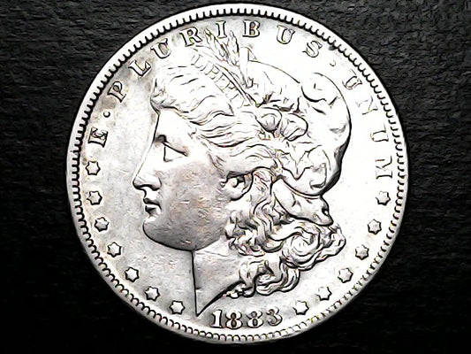 Silver coin with a profile of a person and 'Morgan' inscription on a dark background