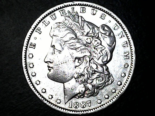 Silver Morgan dollar coin with profile of Liberty on a black background
