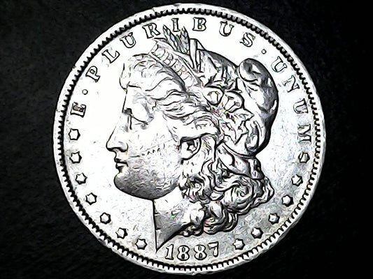 Silver Morgan dollar coin with profile of Liberty on a black background