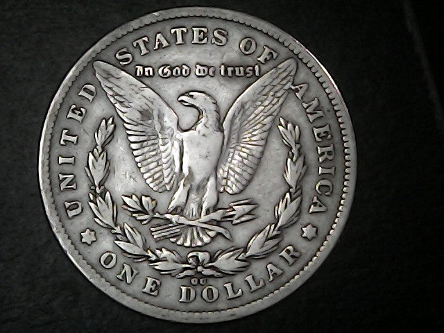 Silver Dollar with an eagle design, 'In God We Trust' and "CC" inscription on a black background