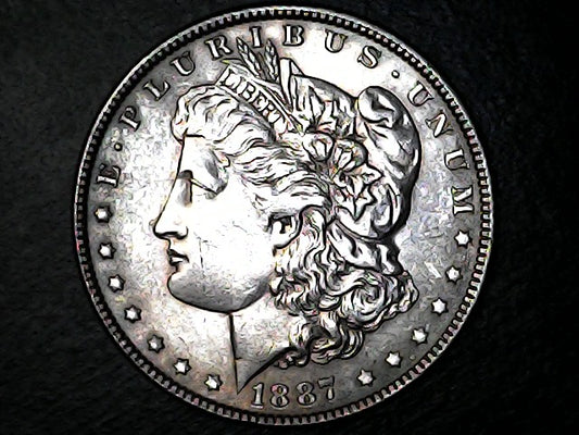 Silver Morgan dollar coin with 'E Pluribus Unum' and '1887' on a black background  