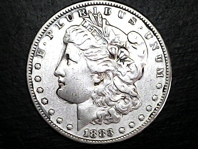 Silver Morgan Dollar Left-facing profile of Liberty wearing a Phrygian cap, with 'LIBERTY', "E PLURIBUS UNUM" and '1883' inscriptions on a black background with case