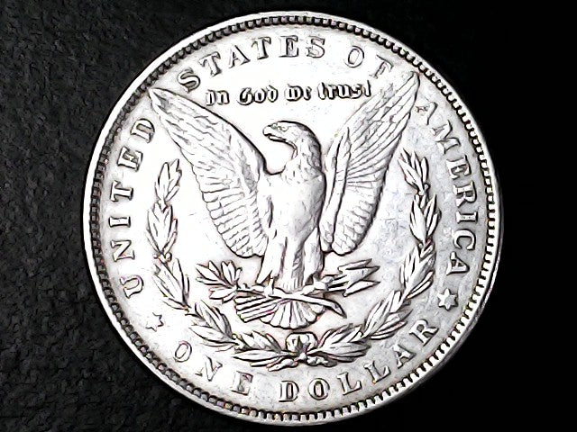 Silver dollar coin with an eagle design on a black background