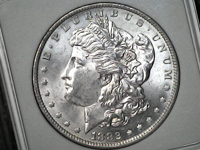 1882-O/S Silver Morgan dollar coin with 'LIBERTY' and 'E PLURIBUS UNUM' inscriptions on a gray background