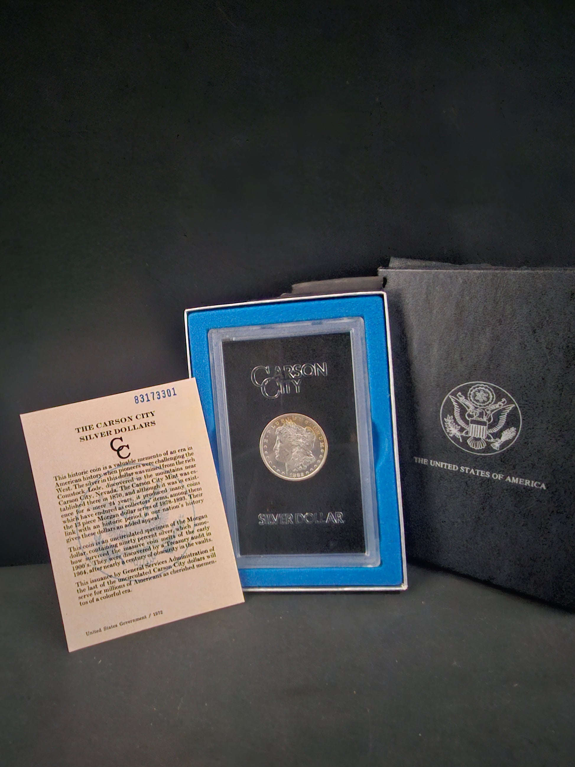 Silver coin in a display case with a certificate on a dark surface