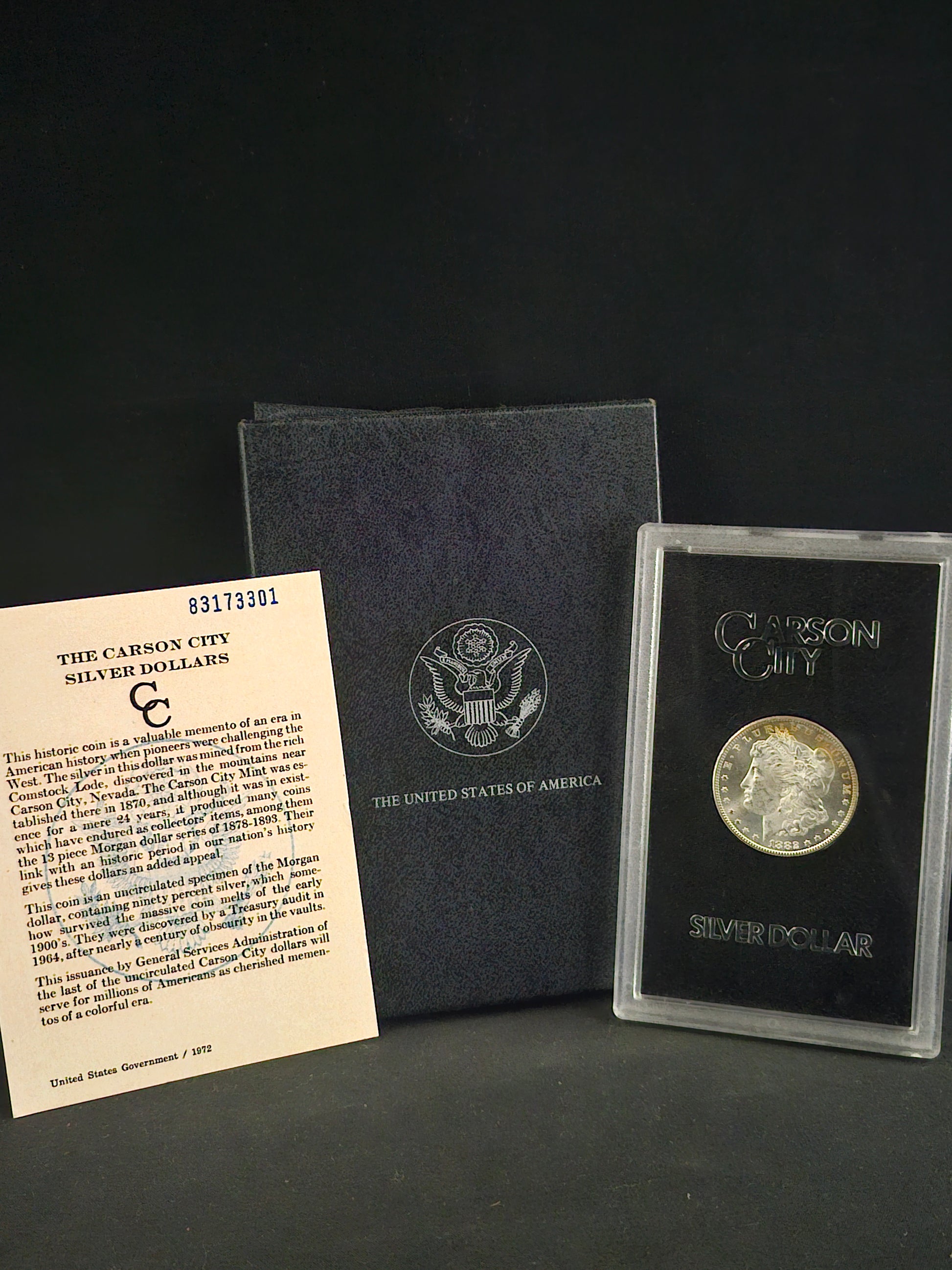Coin in a protective case with an informational card on a dark surface