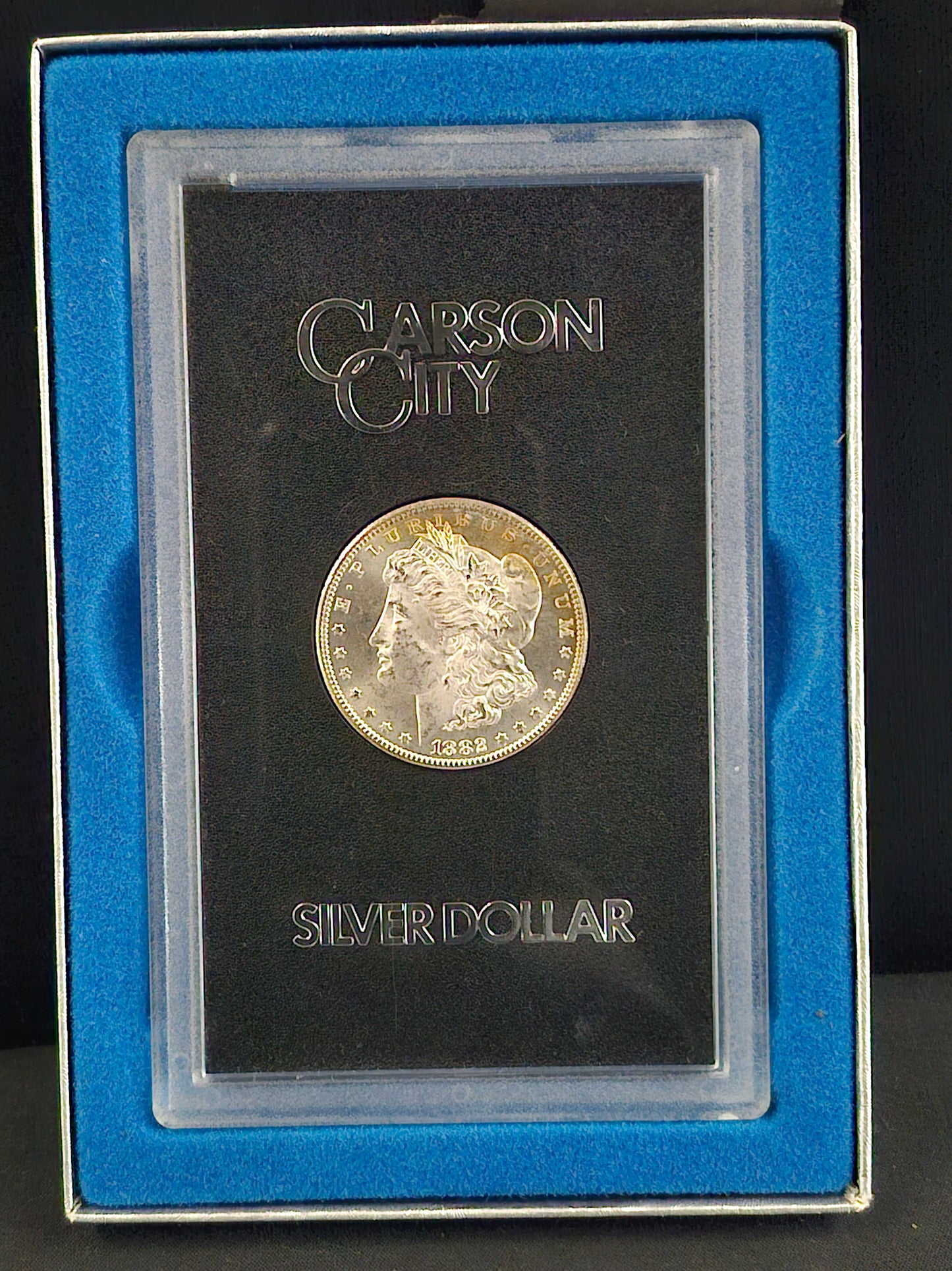 Silver dollar coin in a display case with 'Carson City' branding