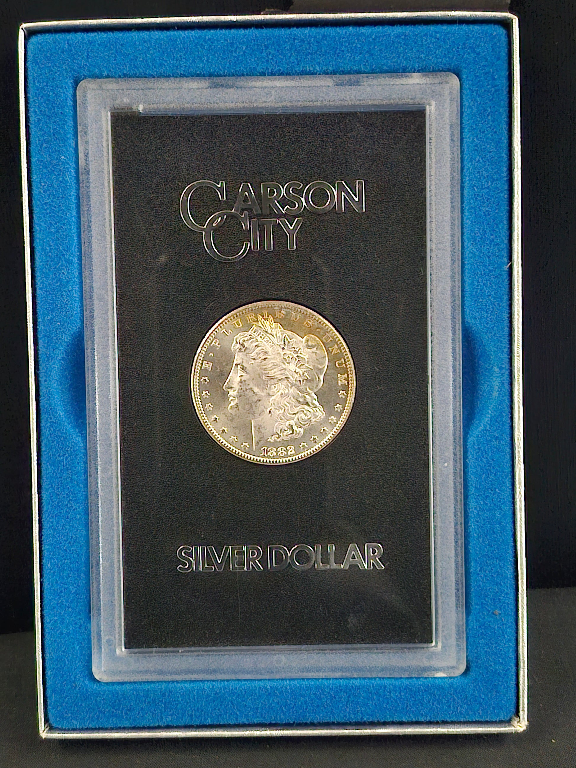 Silver dollar coin in a display case with 'Carson City' branding