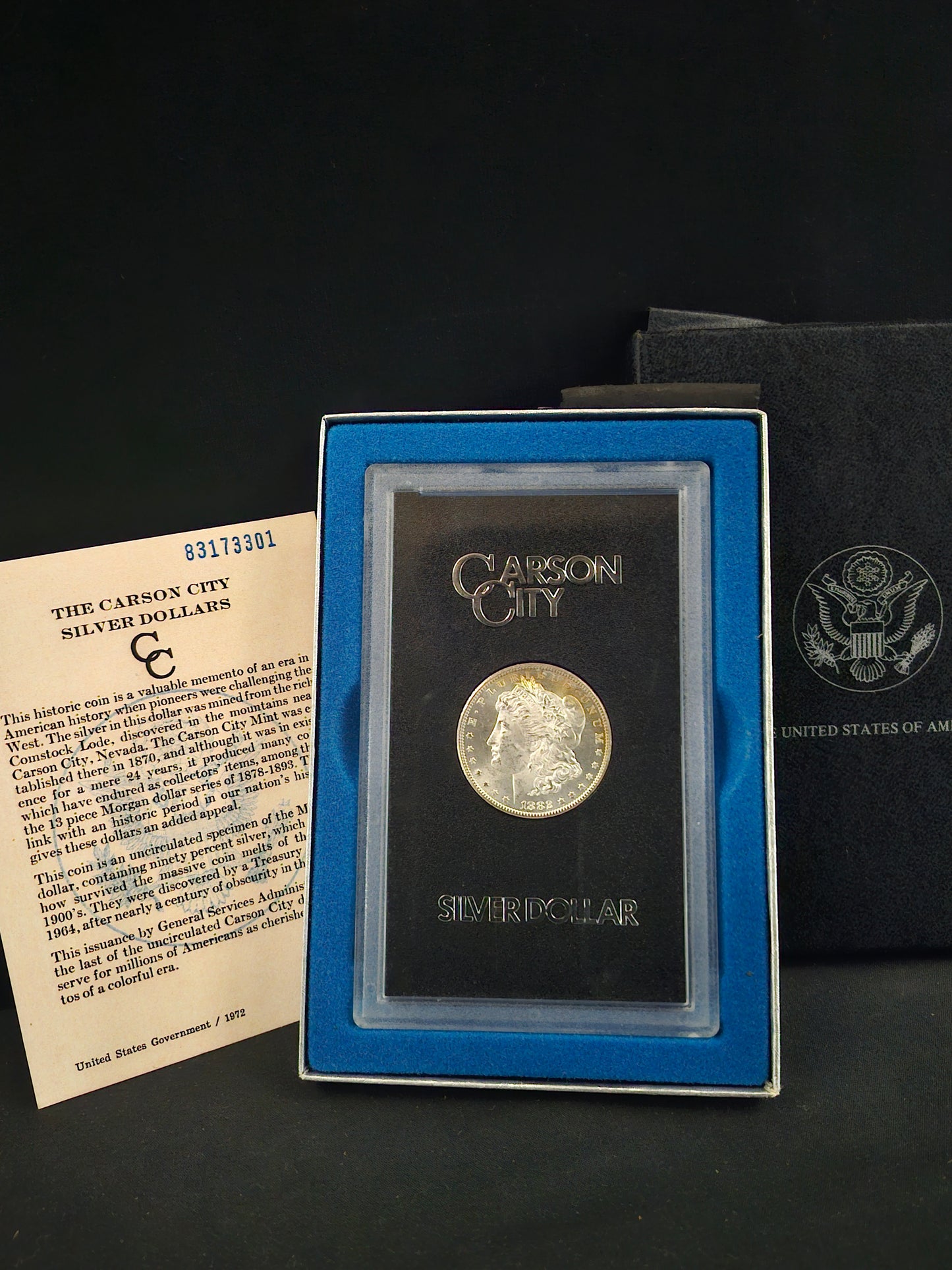Silver coin in a display case with a certificate on a dark background