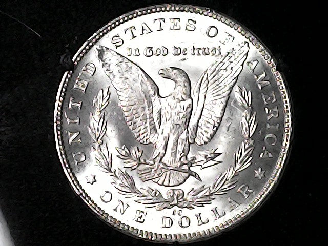 Silver dollar coin with an eagle design on a black background
