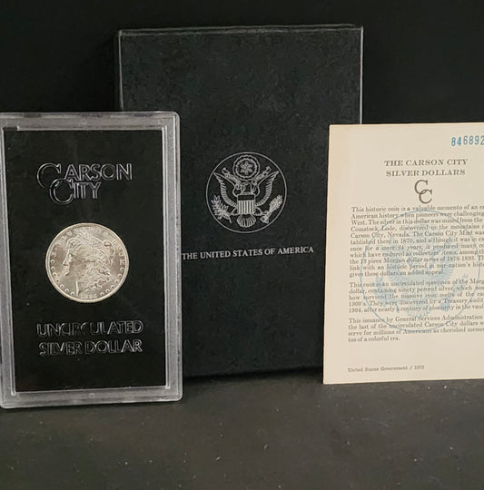 Carson City silver dollar in a display case with an American flag emblem and informational card on a dark background