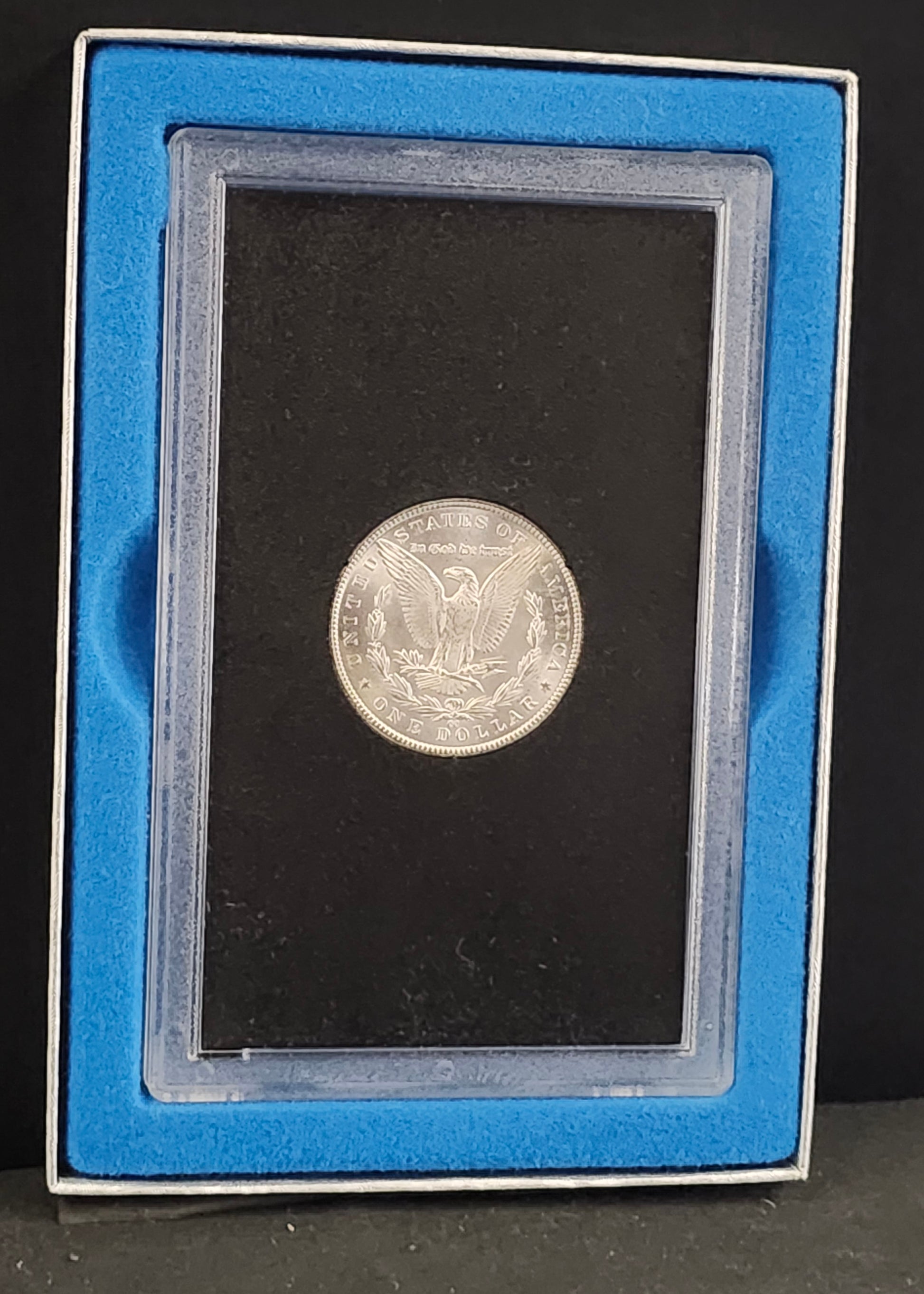 Silver coin in a protective holder against a black background