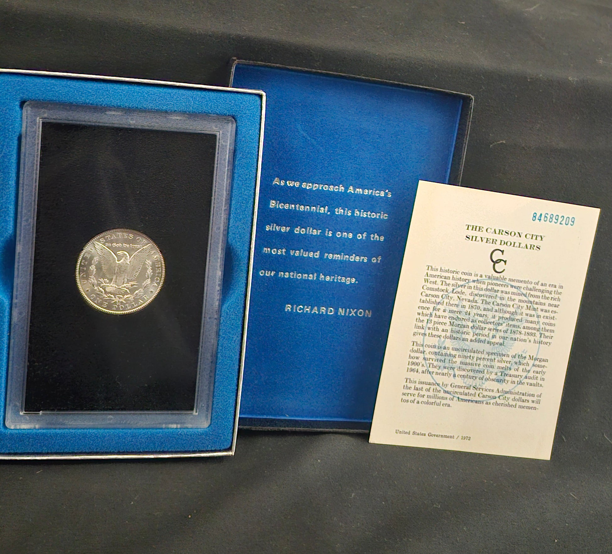 Silver dollar coin in a blue case with a card on a dark surface