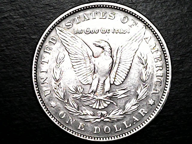 Silver dollar coin with an eagle design on a dark background