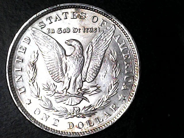 Silver dollar coin with an eagle design on a black background