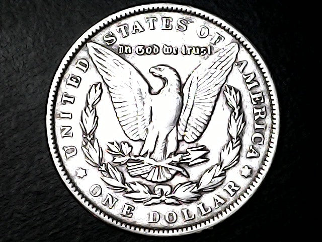 Silver dollar coin with an eagle design on a dark textured background