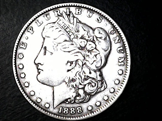 Silver Morgan dollar coin with 'E Pluribus Unum', 'Liberty'  and '1888' inscriptions on a black background