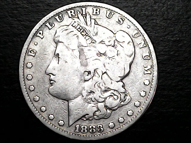 Silver Morgan Dollar Left-facing profile of Liberty wearing a Phrygian cap, with 'LIBERTY', "E PLURIBUS UNUM" and '1883' inscriptions on a black background with case