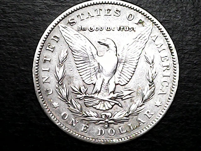 Silver dollar coin with an eagle design on a dark background