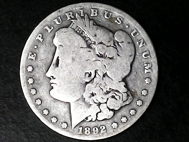 Silver Morgan Dollar Left-facing profile of Liberty wearing a Phrygian cap, with 'LIBERTY', "E PLURIBUS UNUM" and '1892' inscriptions on a black background with case