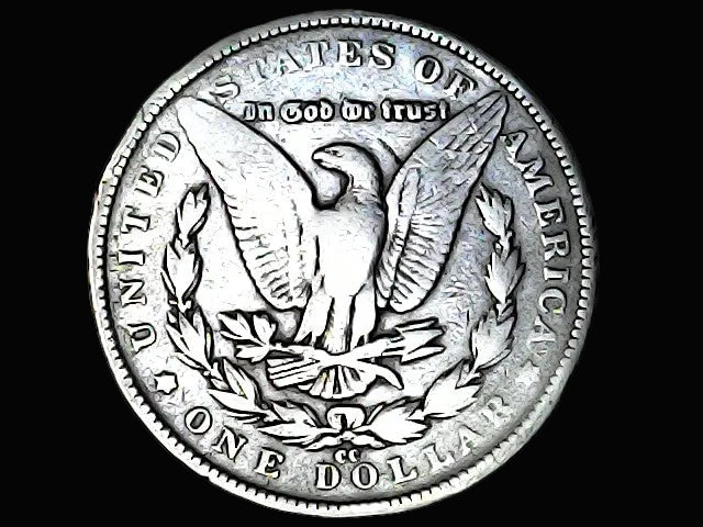 Silver Dollar with an eagle design, 'In God We Trust' and 'CC' inscriptions on a black background 