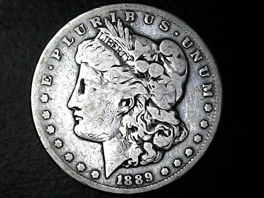 Silver Morgan Dollar with 'E Pluribus Unum', 'Liberty'  and '1889' inscriptions on a black background