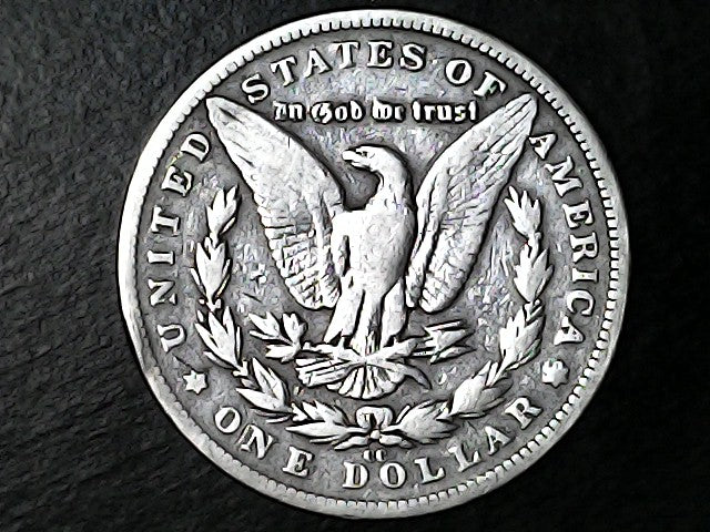 Silver Dollar with an eagle design, 'In God We Trust' and 'CC' inscriptions on a black background 