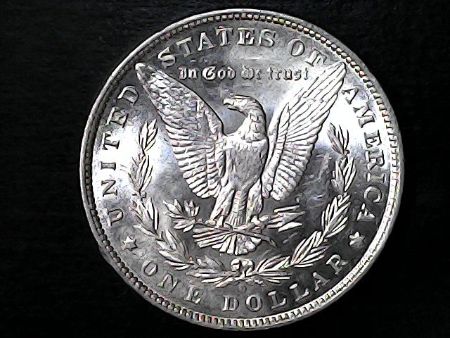 Silver Dollar with an eagle design, 'In God We Trust' and 'O' inscriptions on a black background with a profile of a person and 'E Pluribus Unum' text on a dark background