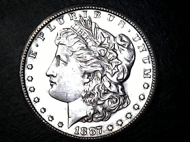 1887 Morgan silver dollar coin with E Pluribus Unum, on a dark background.