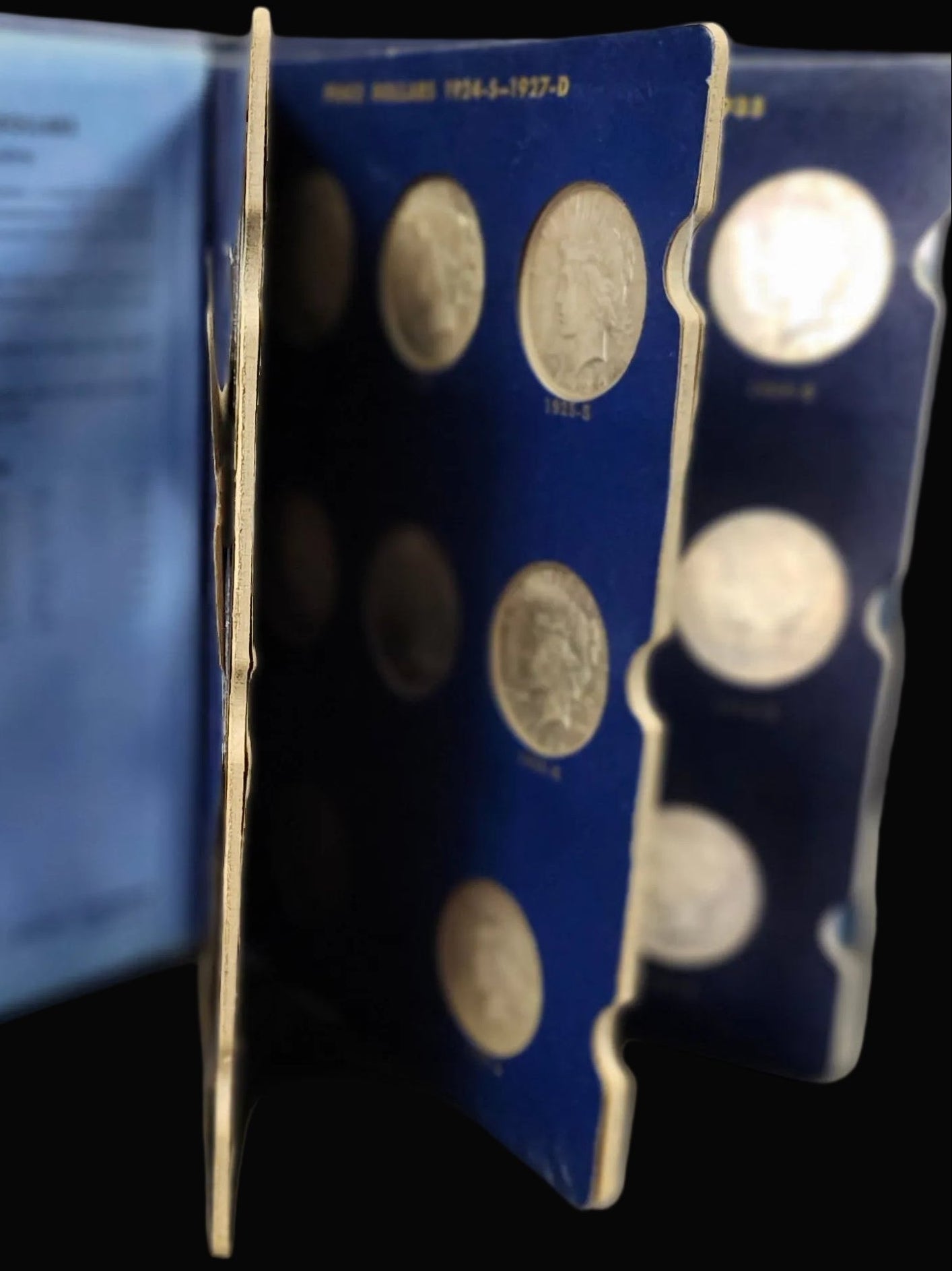 Set of silver Peace Dollars in a blue Peace Book on a dark surface