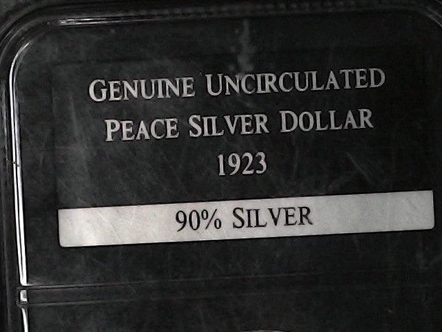 Label on a case indicating 'Genuine Uncirculated Peace Silver Dollar 1923 90% Silver'.